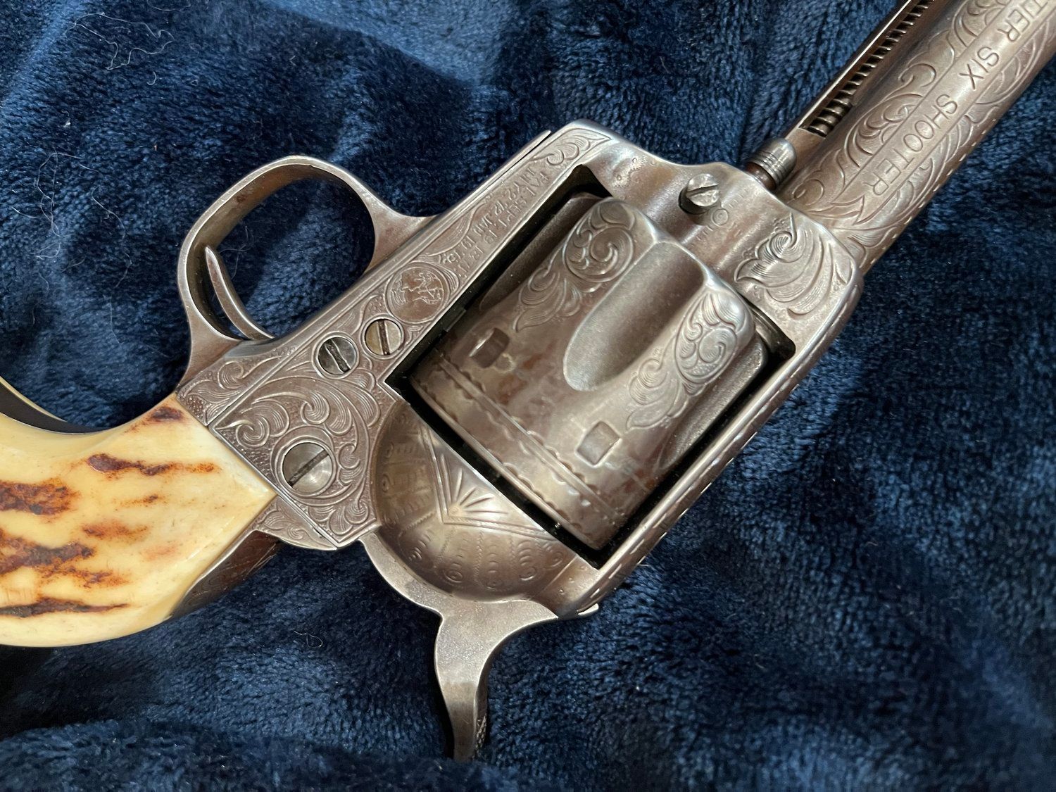 Close-up of an ornate, antique revolver with a light handle and detailed engravings.