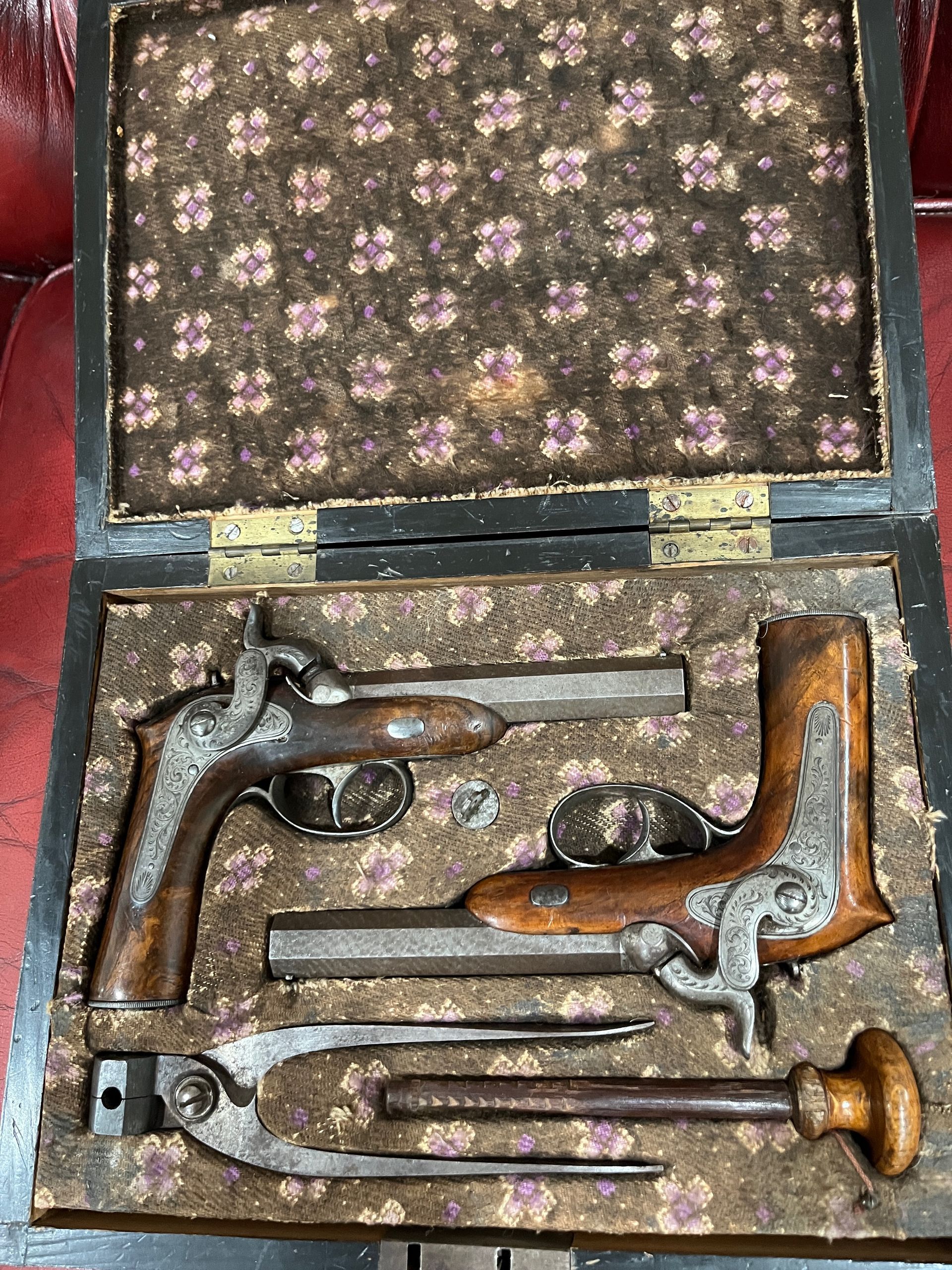 Two antique, wooden-handled pistols on a red surface.