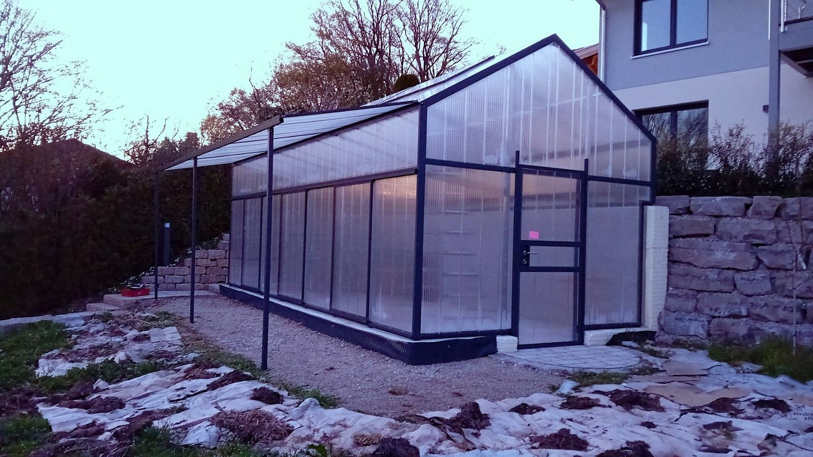 Freistehendes Gewächshaus mit stufigem Fundament und Klappelmenten und anthrazit Farbe, 3,5x7m groß.