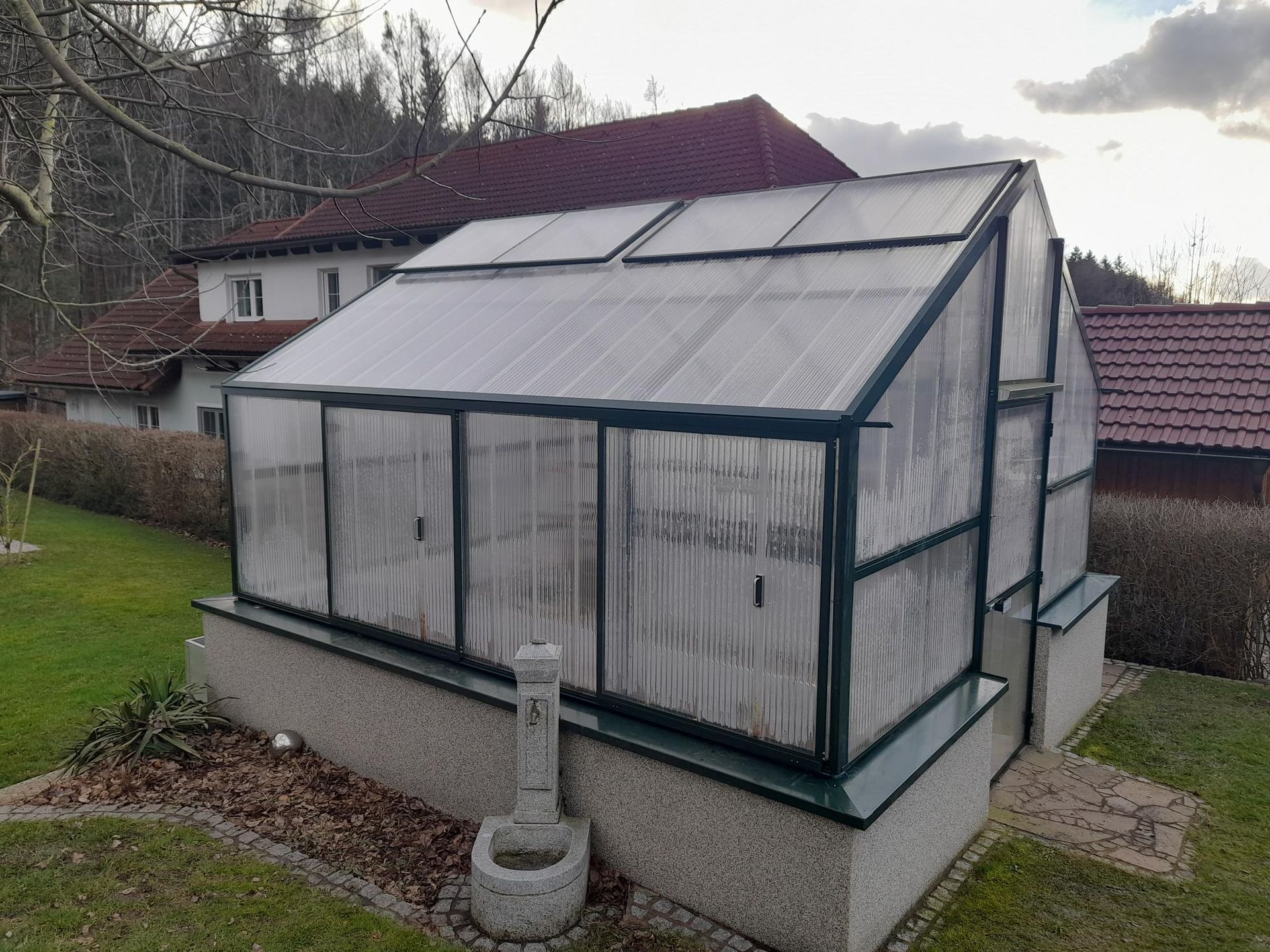 Ein grünes freistehendes Gewächshaus mit Hochbeete, 4x4m groß.