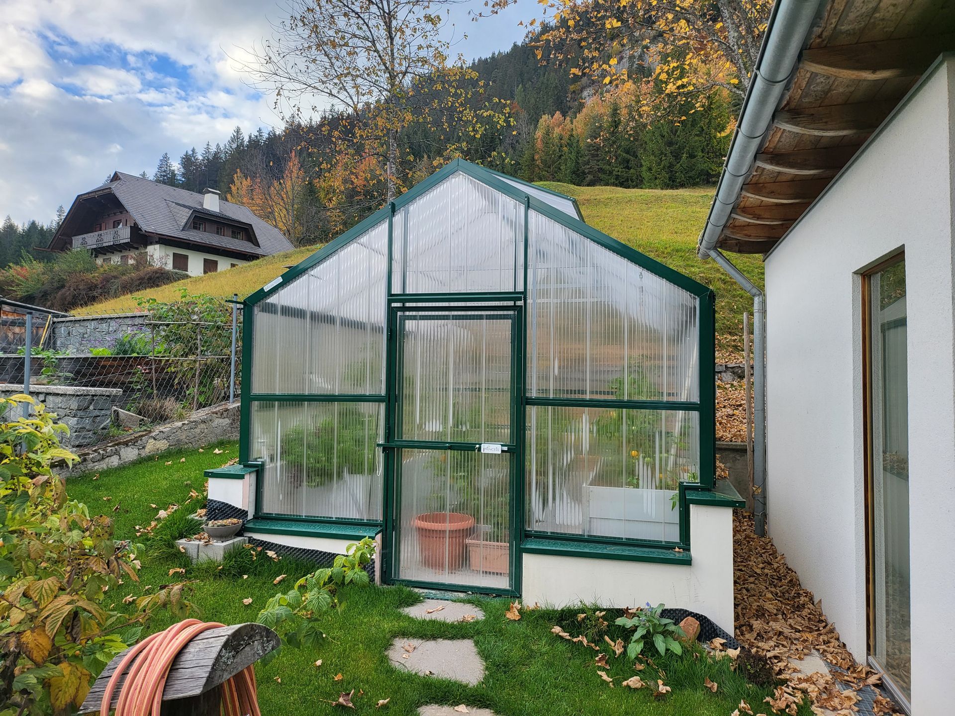 Ein grünes Gewächshaus mit Hochbeete, 3,5x4,7m groß.