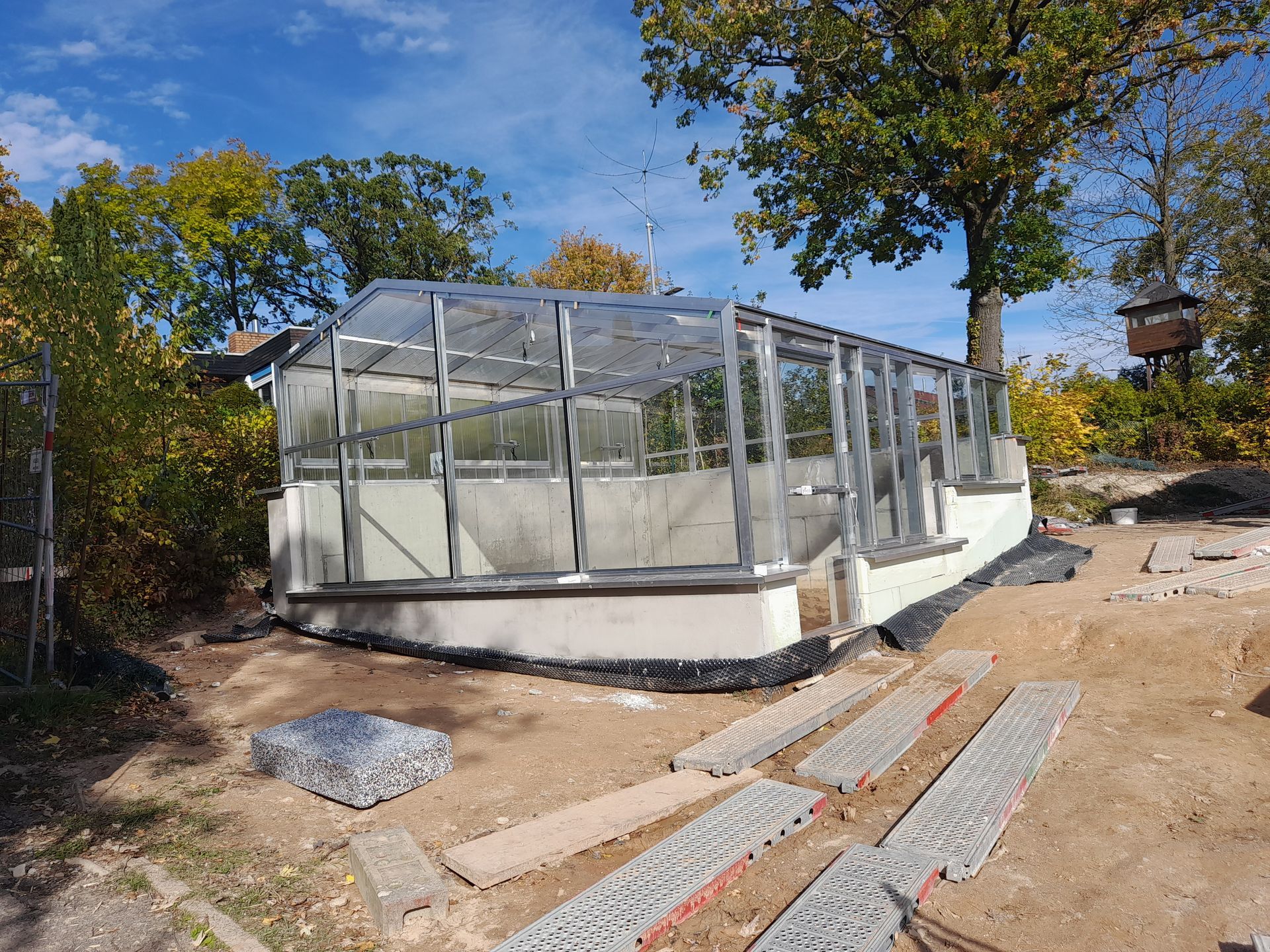 Freistehendes Gewächshaus mit asymetrischem Satteldach und stufigem Fundament. Komplett in Echtglas Ausführung.