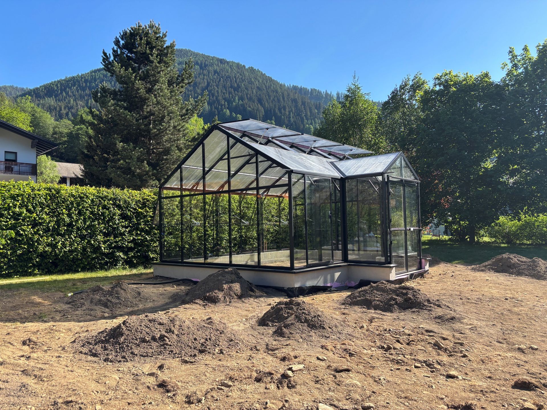 Freistehendes Gewächshaus mit Satteldach und Graupe. Haupttrakt 4,5x6m, Graupe 2x1m. Seitenwände in Echtglasausführung. Gerüst in schwarze Farbe.
