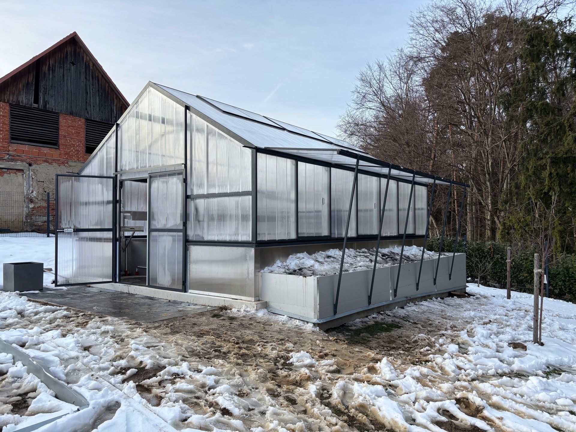 Gewächshaus in Farbe anthrazit mit Hochbeete und seitlichen Klappelementen, auf Isolierfertigfundament aufgesetzt. Größe 5x7m.