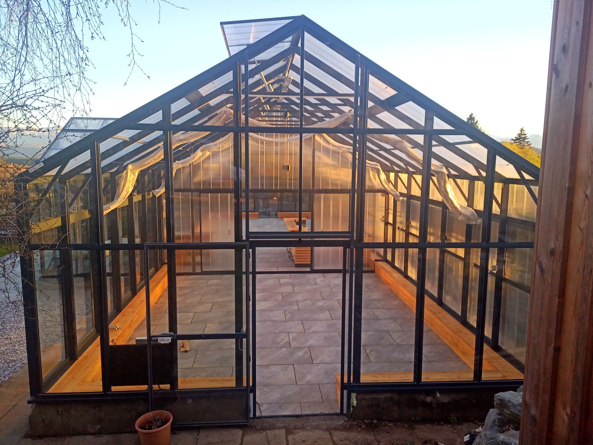 Freistehendes Gewächshaus mit Graupe. Haupttrakt 6x18,5m, Graupe 5x3m Groß. Seitenwände in Echtgals, Dach aus Thermoacryl. Gerüst in anthrazit Farbe.