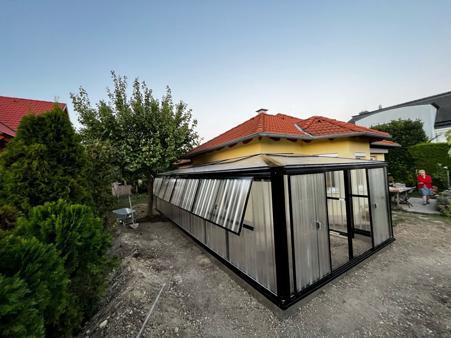 Gewächshaus mit asymetrische Satteldach-Pultdach Kombination 4x4m groß, davon 2 m an das Haus angebaut.
