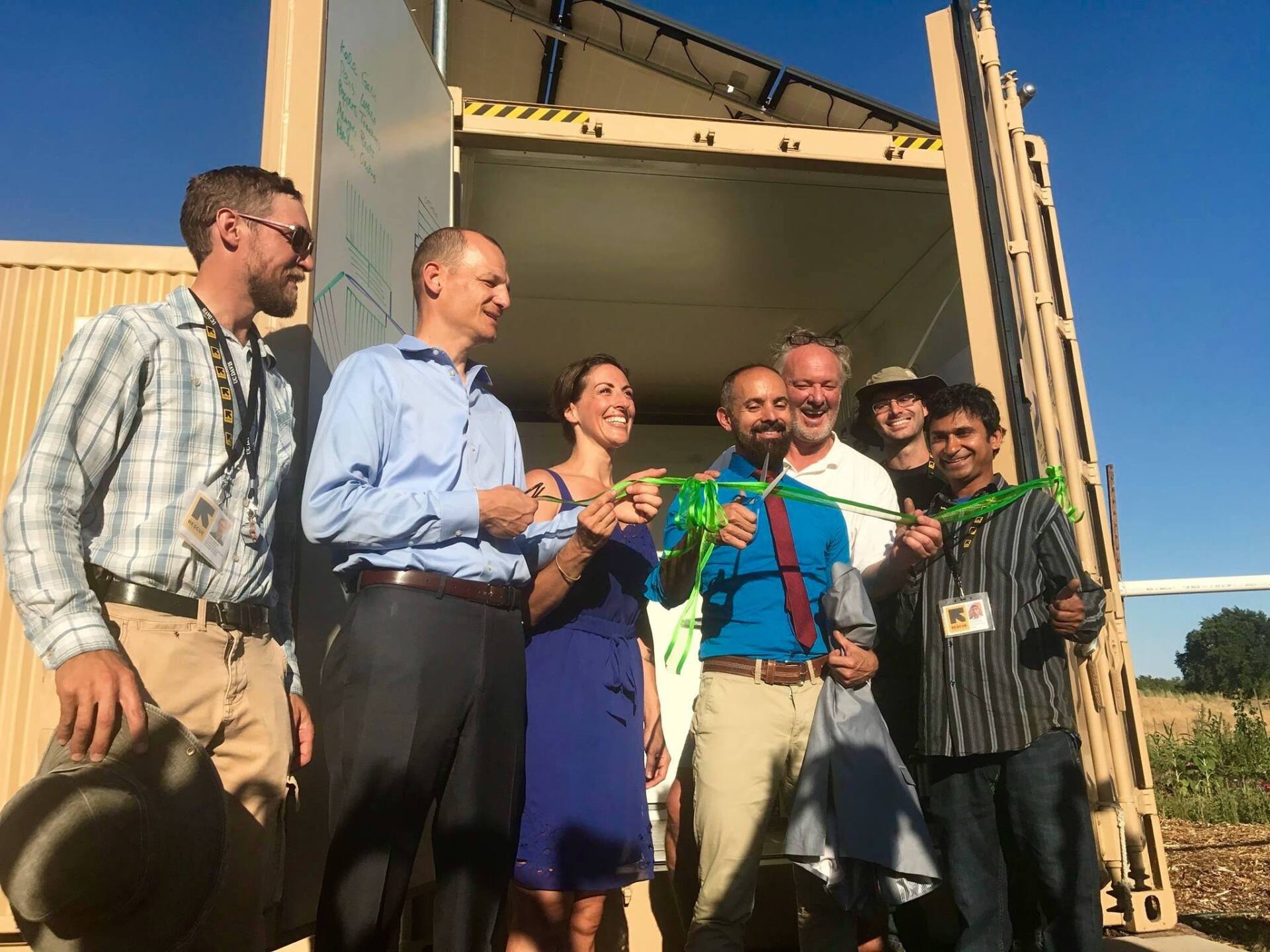 A group of people from the International Rescue Committee smiling in front of their Farm from a Box