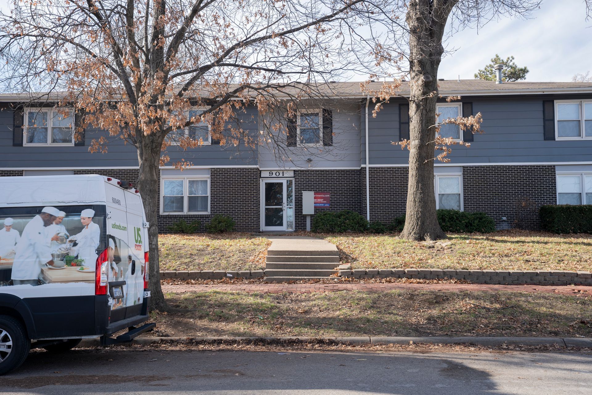 Apartment building with a food delivery van in the foreground.