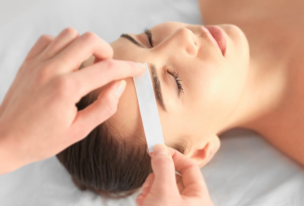 A Woman Is Getting Her Eyebrows Waxed at A Beauty Salon — Villa Nails & Beauty in Cannonvale, QLD