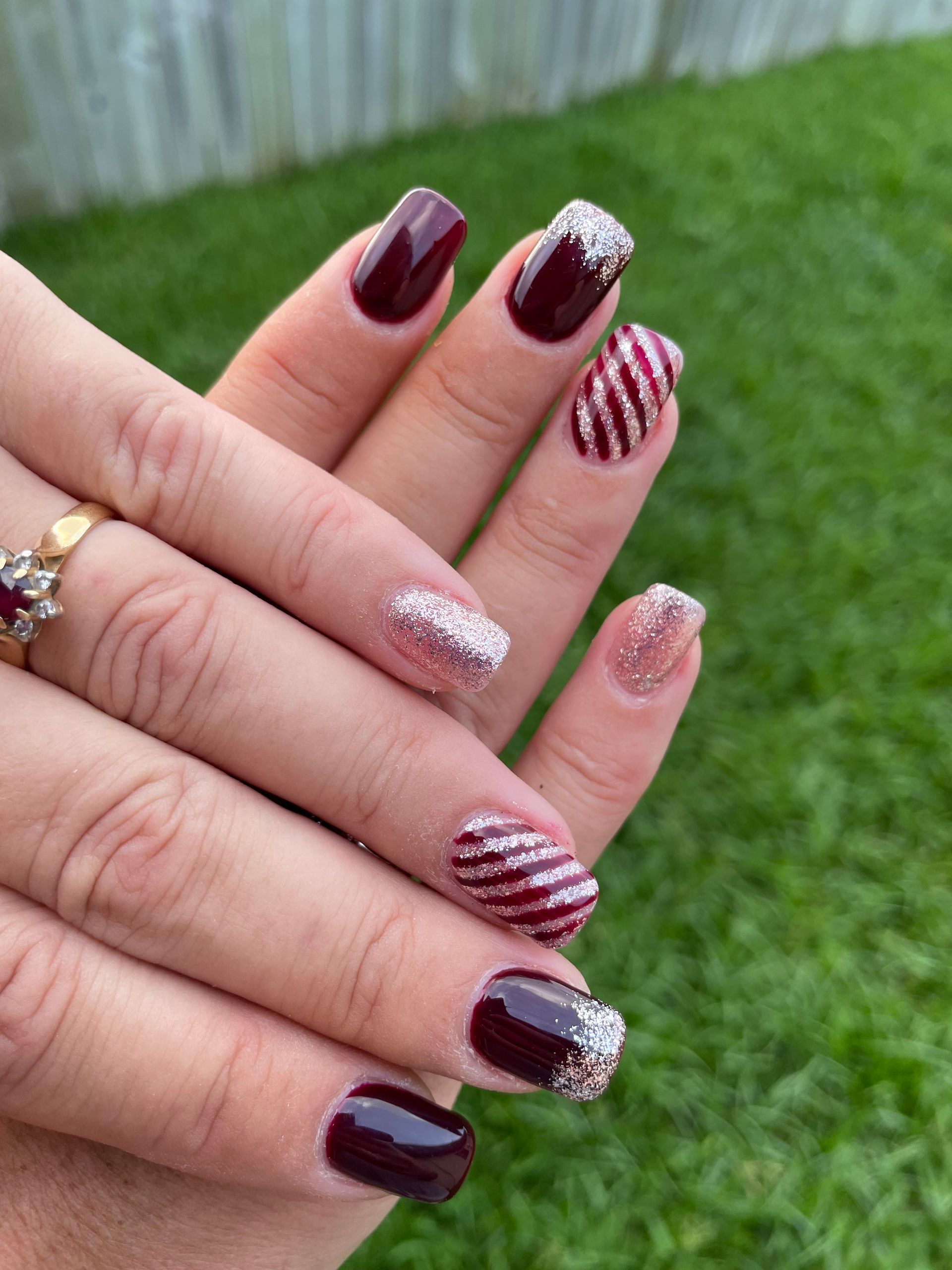 Hands with Burgundy and Silver Glitter Nail Art Displayed Outdoors — Villa Nails & Beauty in Cannonvale, QLD