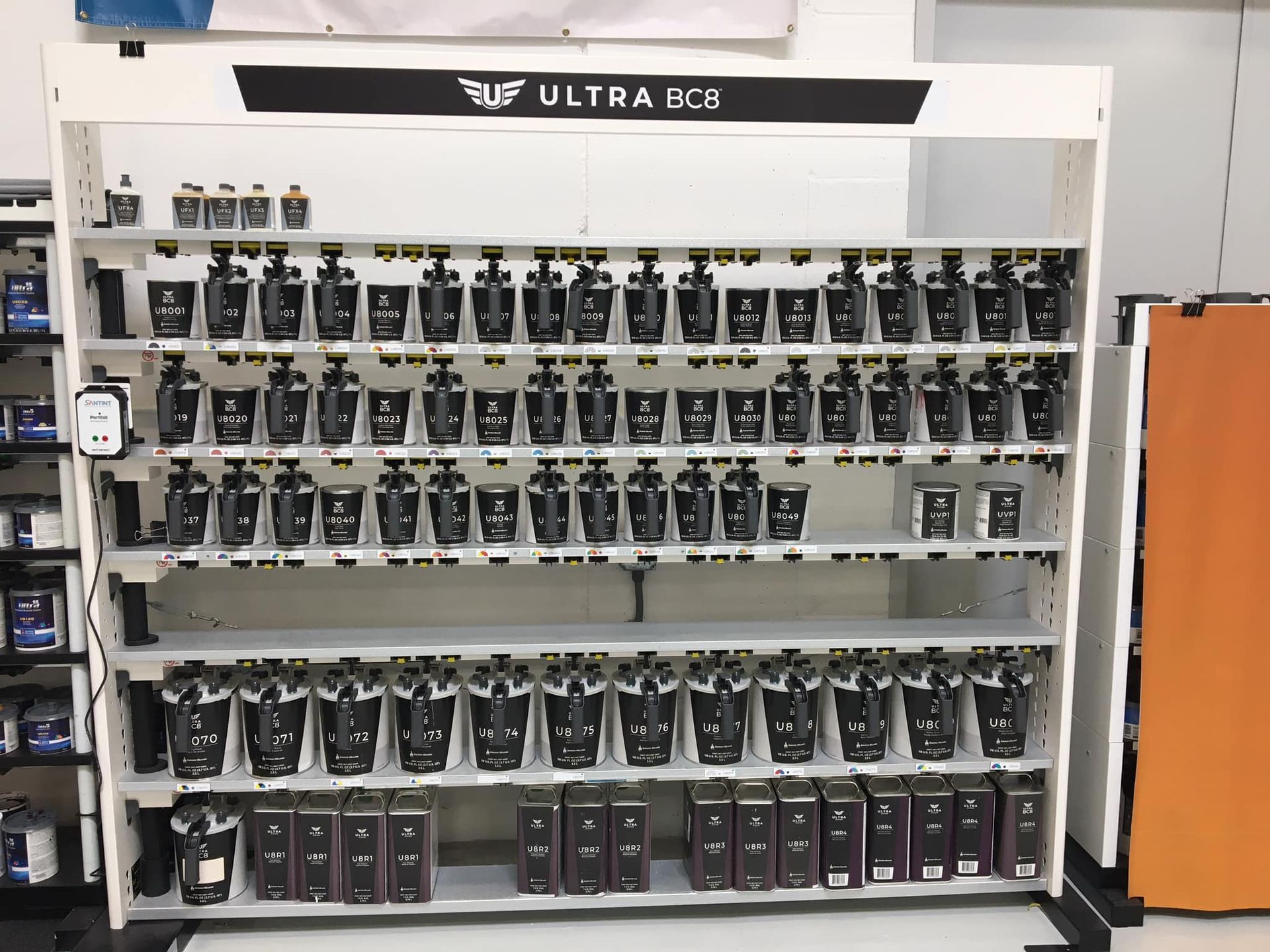 A display shelf filled with black paint containers, labeled 