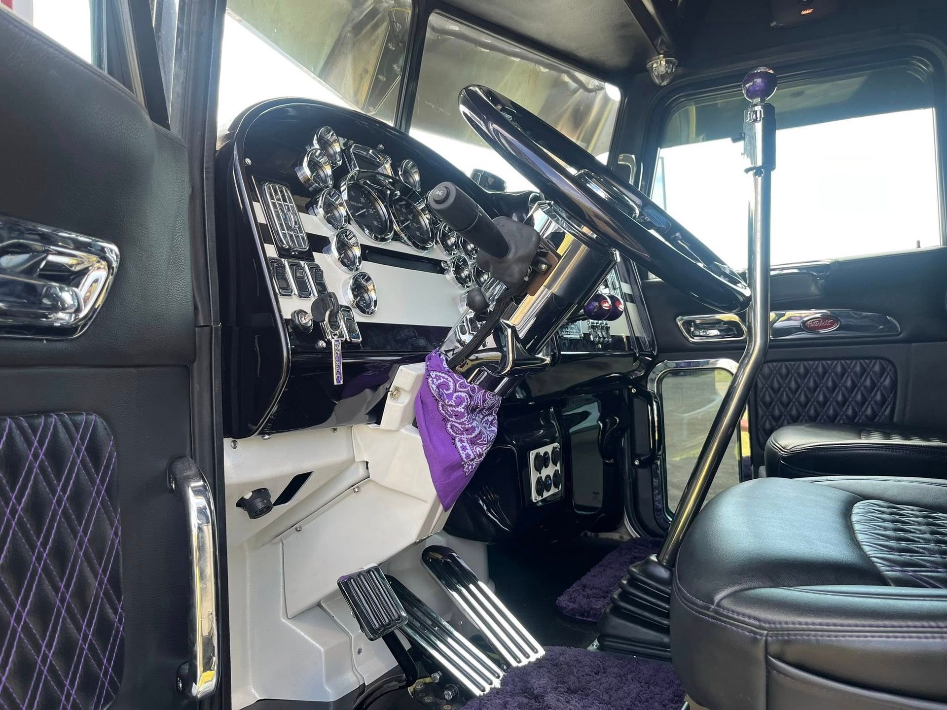 Interior view of a custom black truck with purple accents and a chrome dashboard.