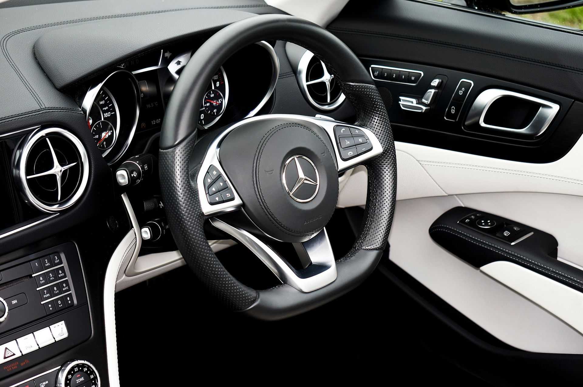 Luxury Mercedes-Benz car interior with black-and-white leather seats, dashboard, and steering wheel