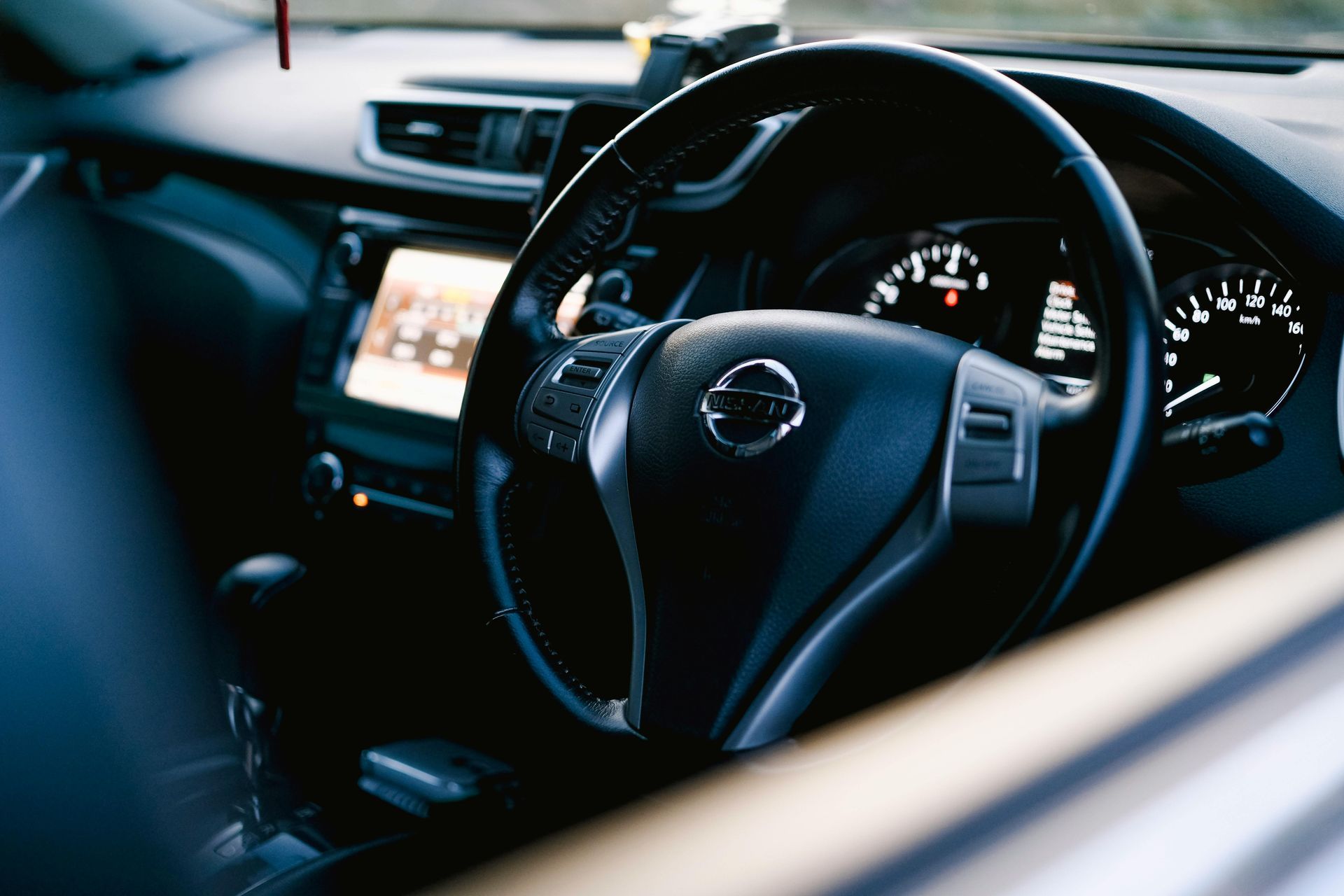 Car interior with a black steering wheel and illuminated dashboard at night