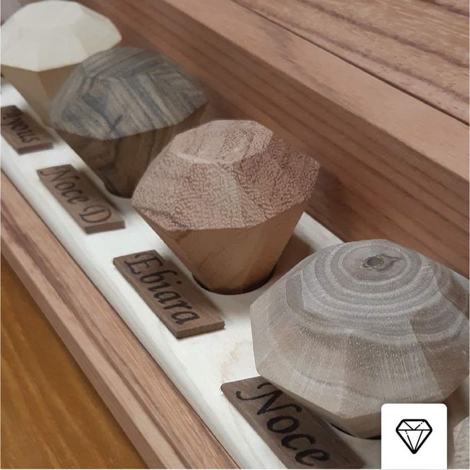Una piccola scatola di legno marrone lucido, probabilmente un'urna cineraria, è appoggiata su una superficie chiara, con un opuscolo nelle vicinanze.