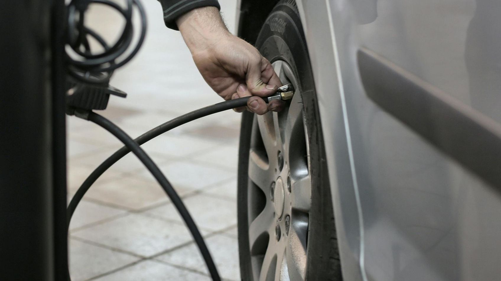 person filling up their car tyres with air