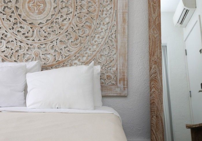 Bed with white pillows and intricately carved wooden headboard.