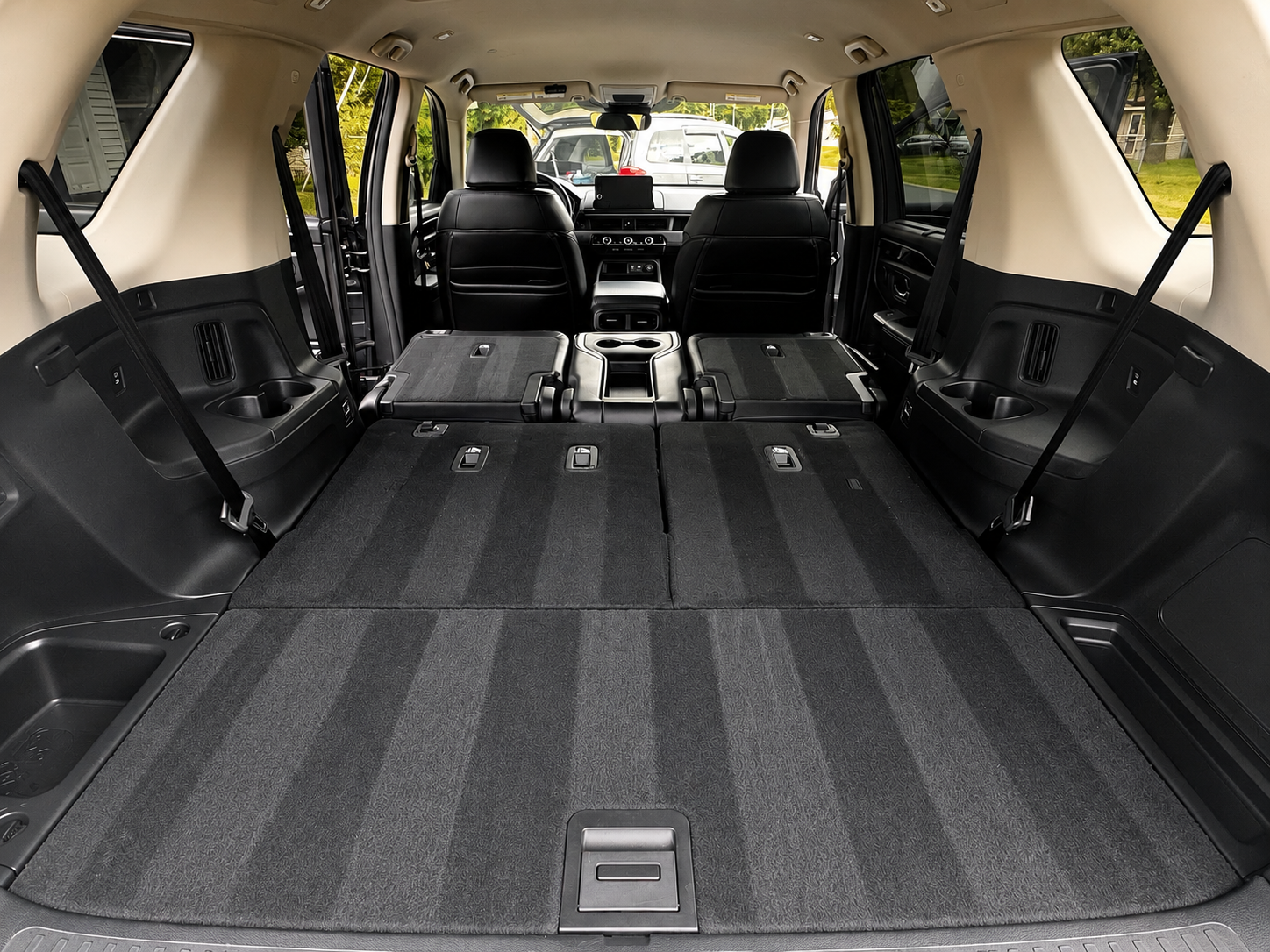 A view inside a vehicle showing black leather second-row seats and a folded third-row seat on black carpet.