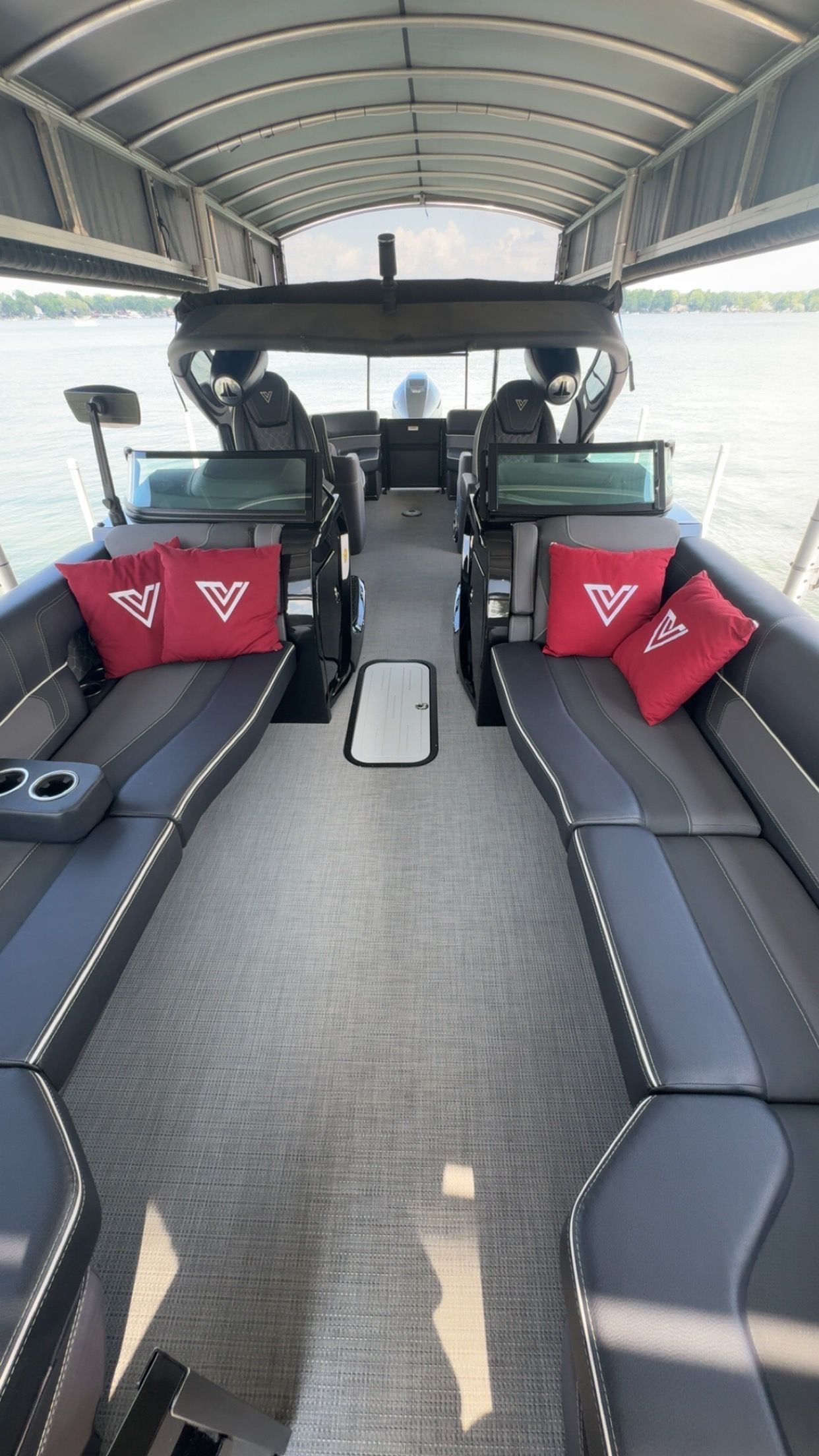 Interior view of a black leather car cabin with a bottle in the center console and a window view of trees and grass.