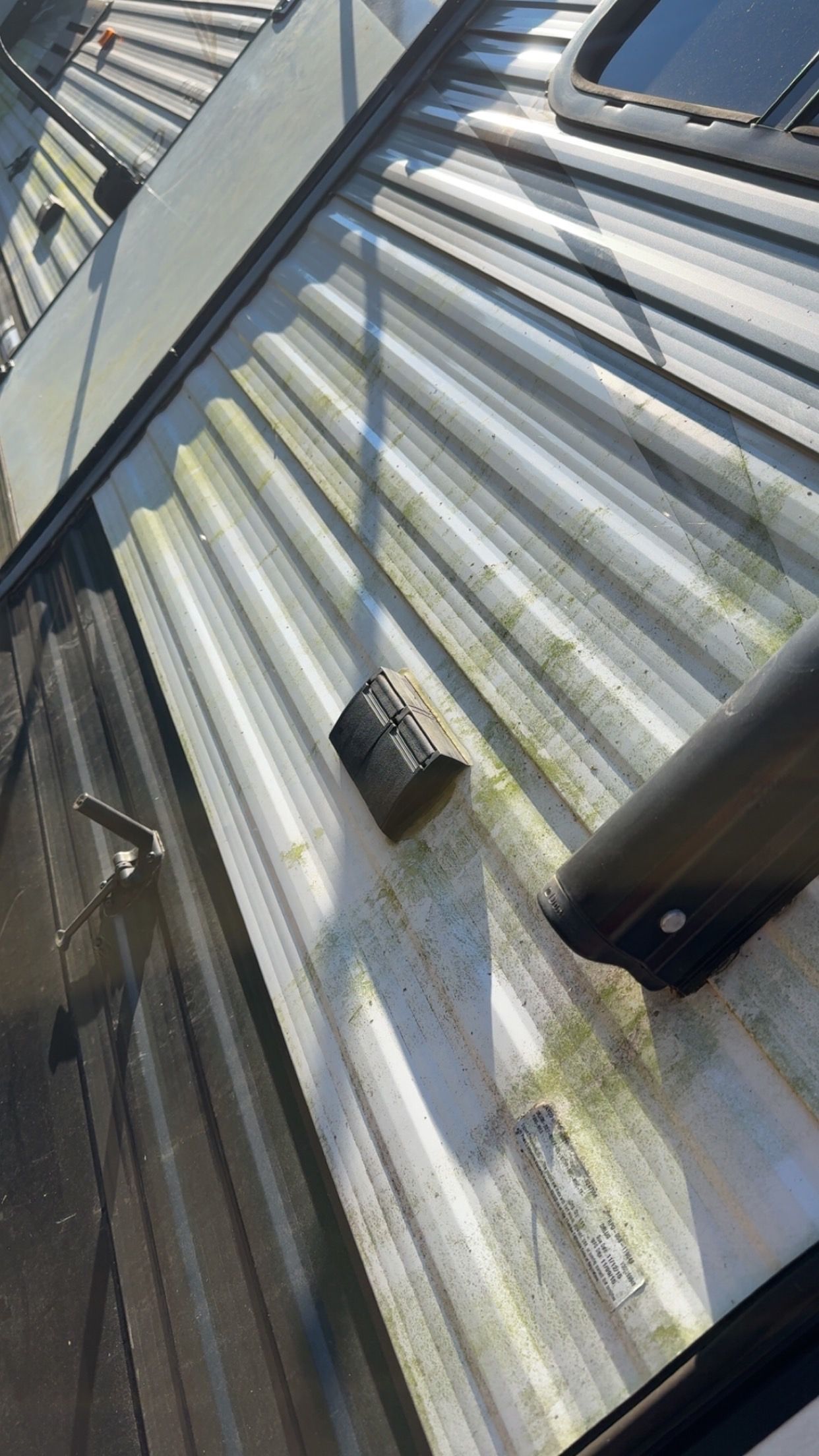 Corrugated metal roof with a small vent and weathered surface in a narrow outdoor area