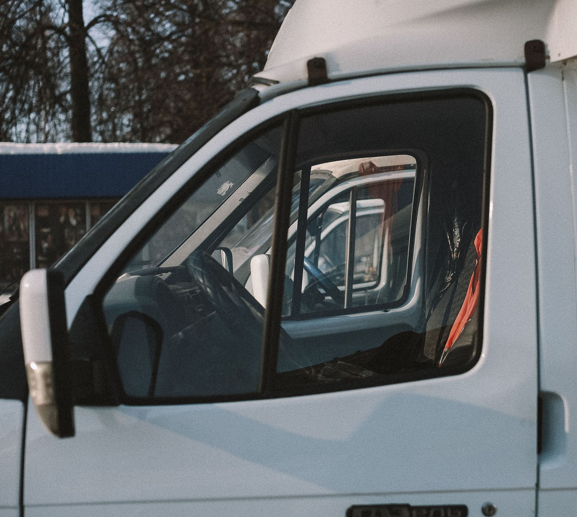 White van side window with a reflection of another vehicle and a snowy outdoor background