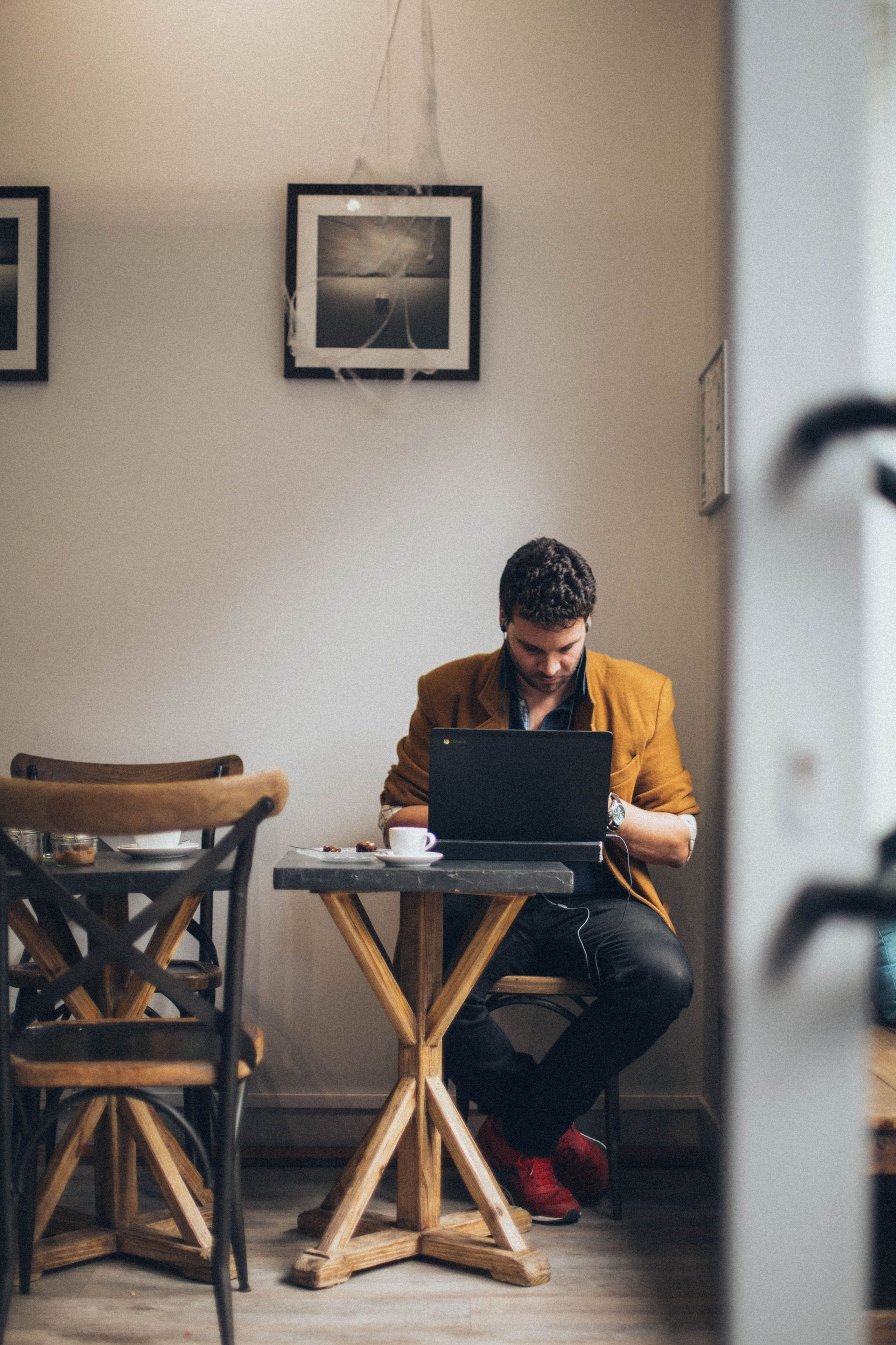 Person working on a laptop at a small table in a quiet café or workspace.
