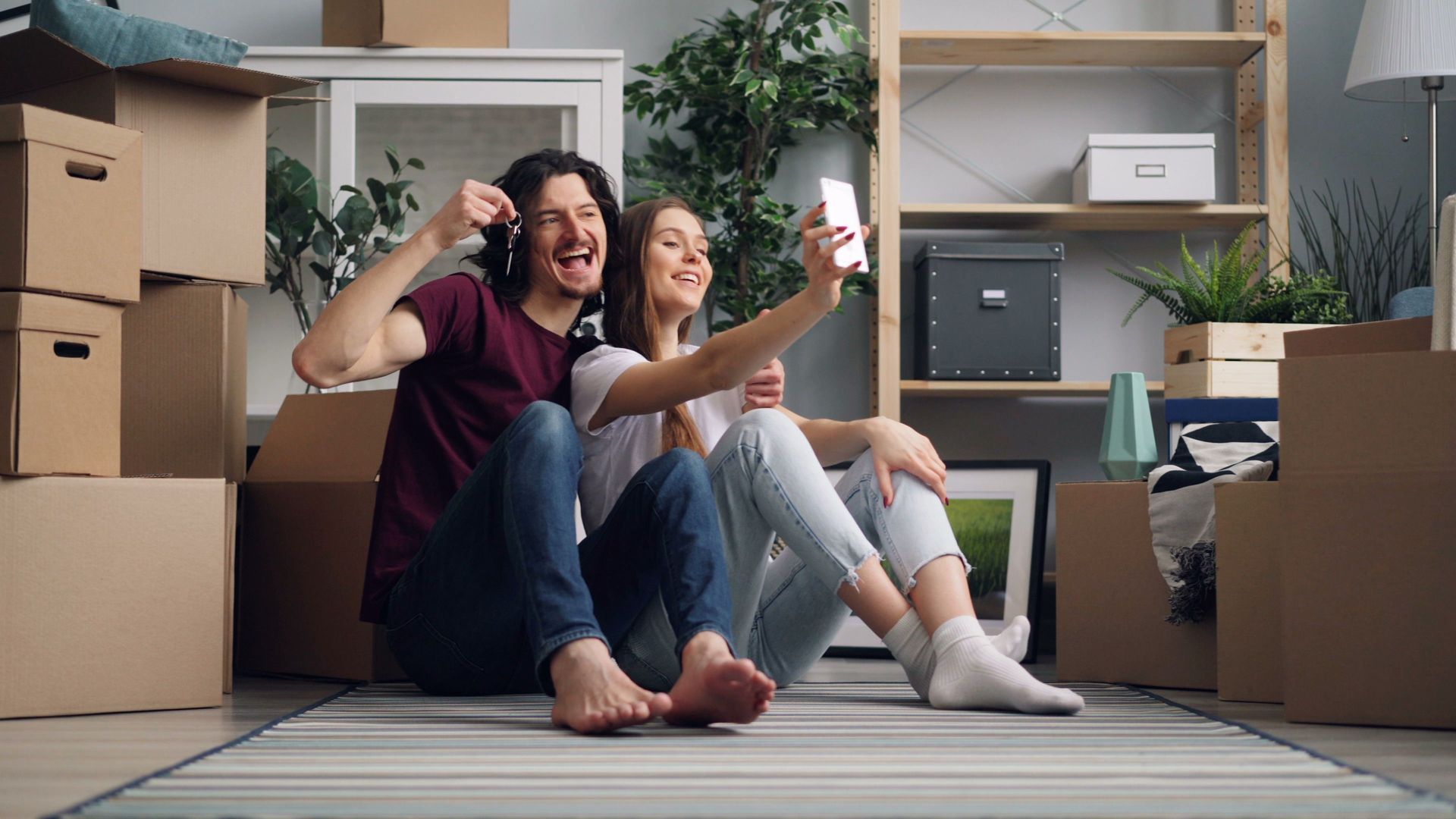 Person carrying boxes into a house with a “House for Rent” sign in the yard