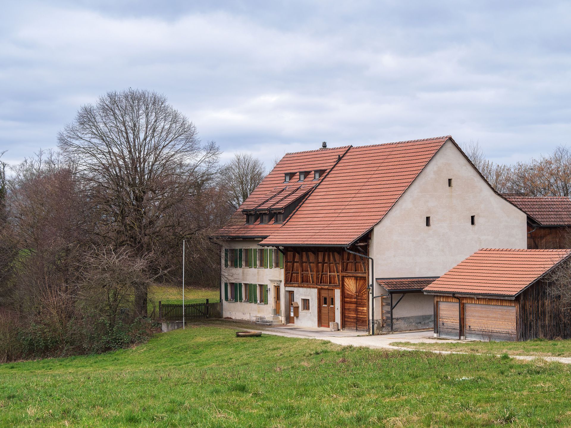 Two houses with dark roofs and a brick facade under a cloudy sky