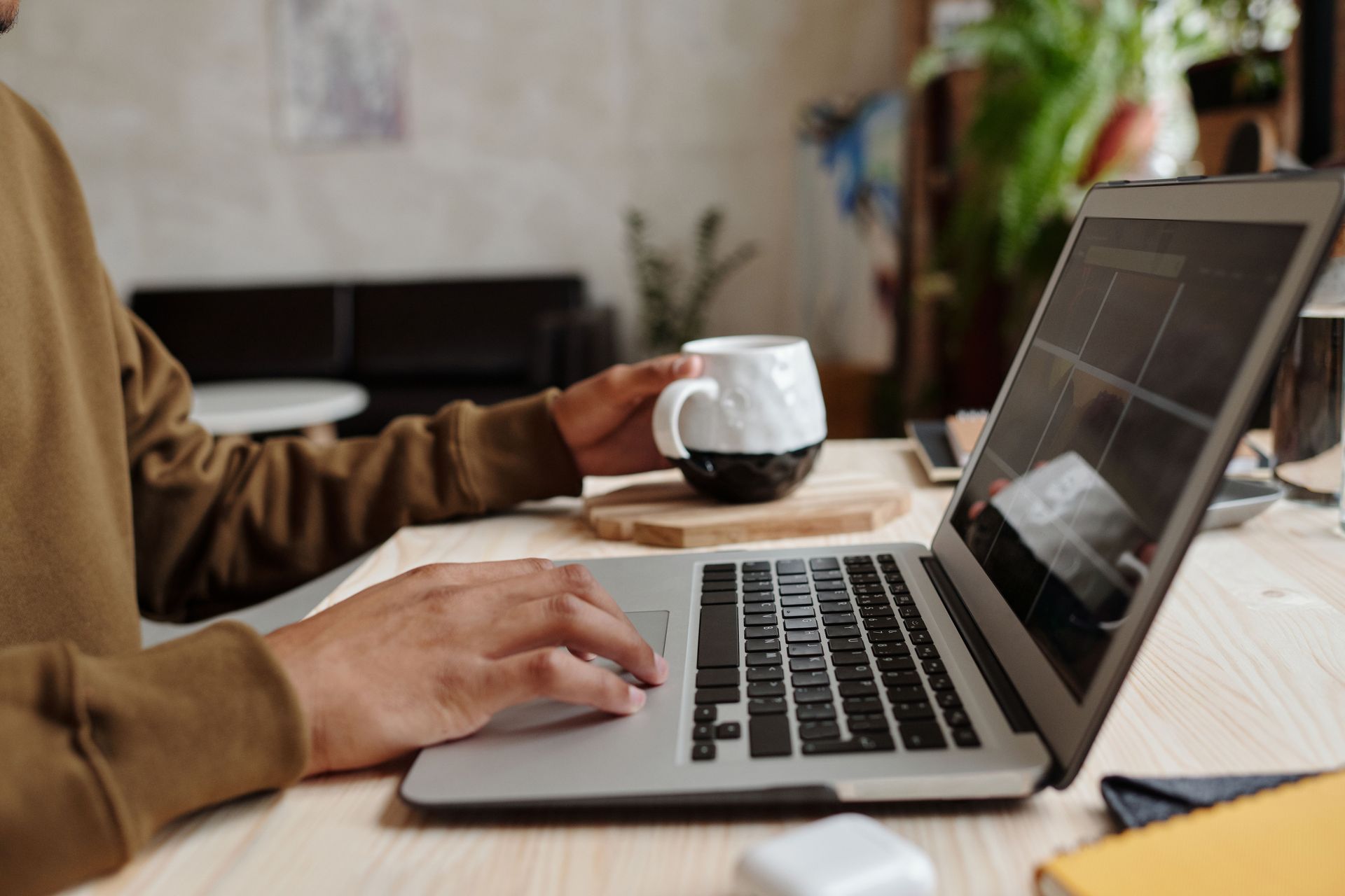 Person typing on a laptop beside a cup of coffee on a desk