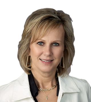 Professional headshot of a smiling woman in a white blazer against a white background