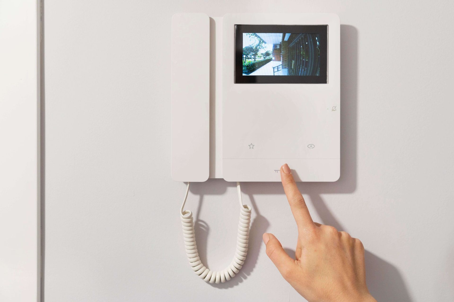 A person is pressing a button on a video door phone.