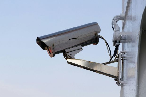 A bunch of security cameras on a pole against a blue sky