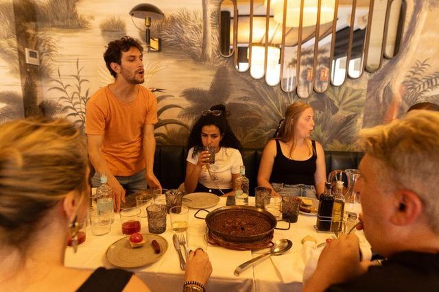 A host explaining paella to guests