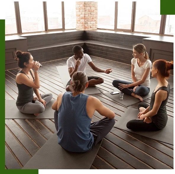 Group of people sitting in a circle on yoga mats.