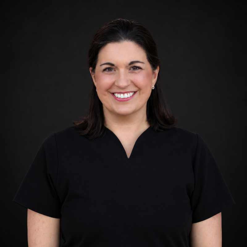 Smiling person in black shirt against a dark background