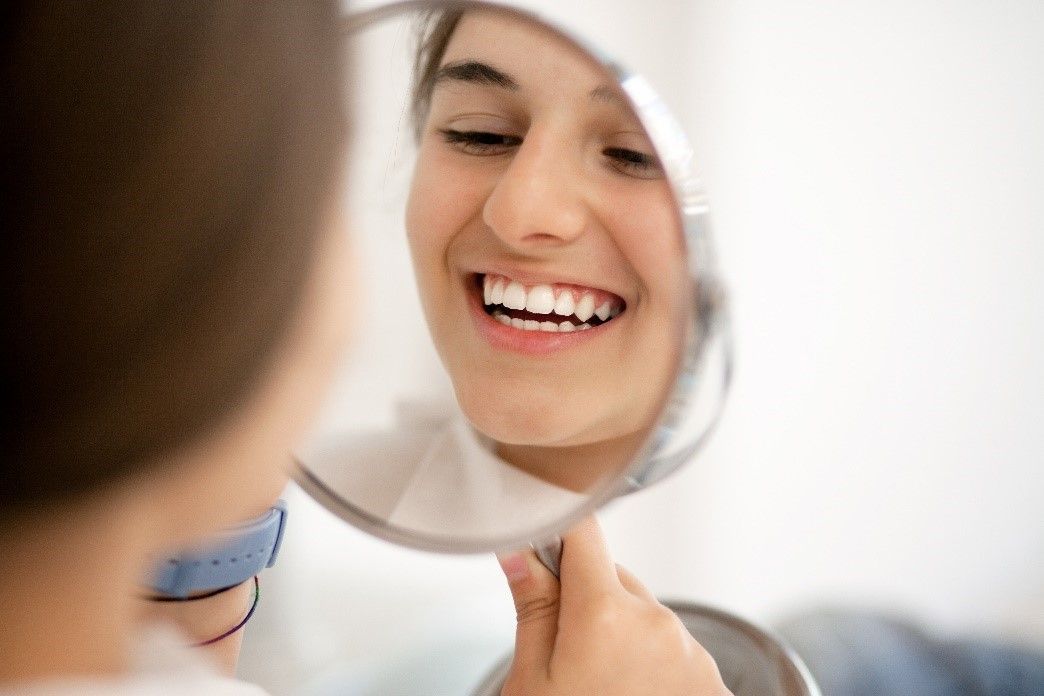 A Woman Looking at Her Teeth in the Mirror | Tooth-Colored Fillings