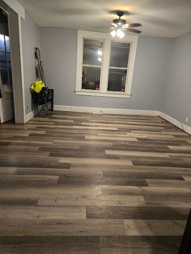 Empty room with gray walls, wood-look flooring, ceiling fan, and a window.