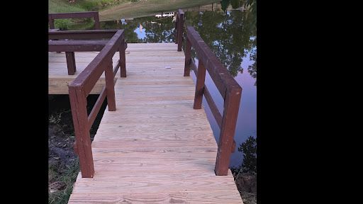 Wooden boardwalk path with dark railings crossing over water at dusk.