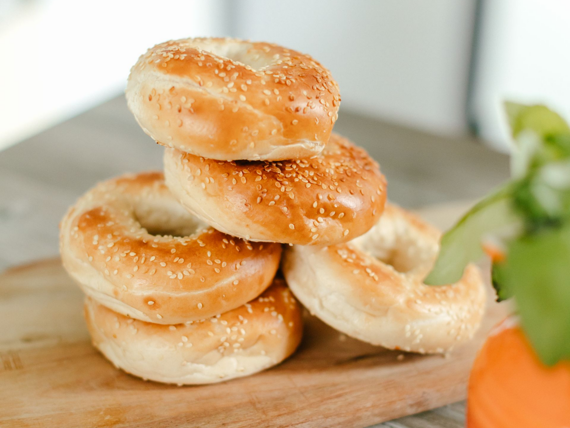 Stack of sesame bagels on a wooden board.