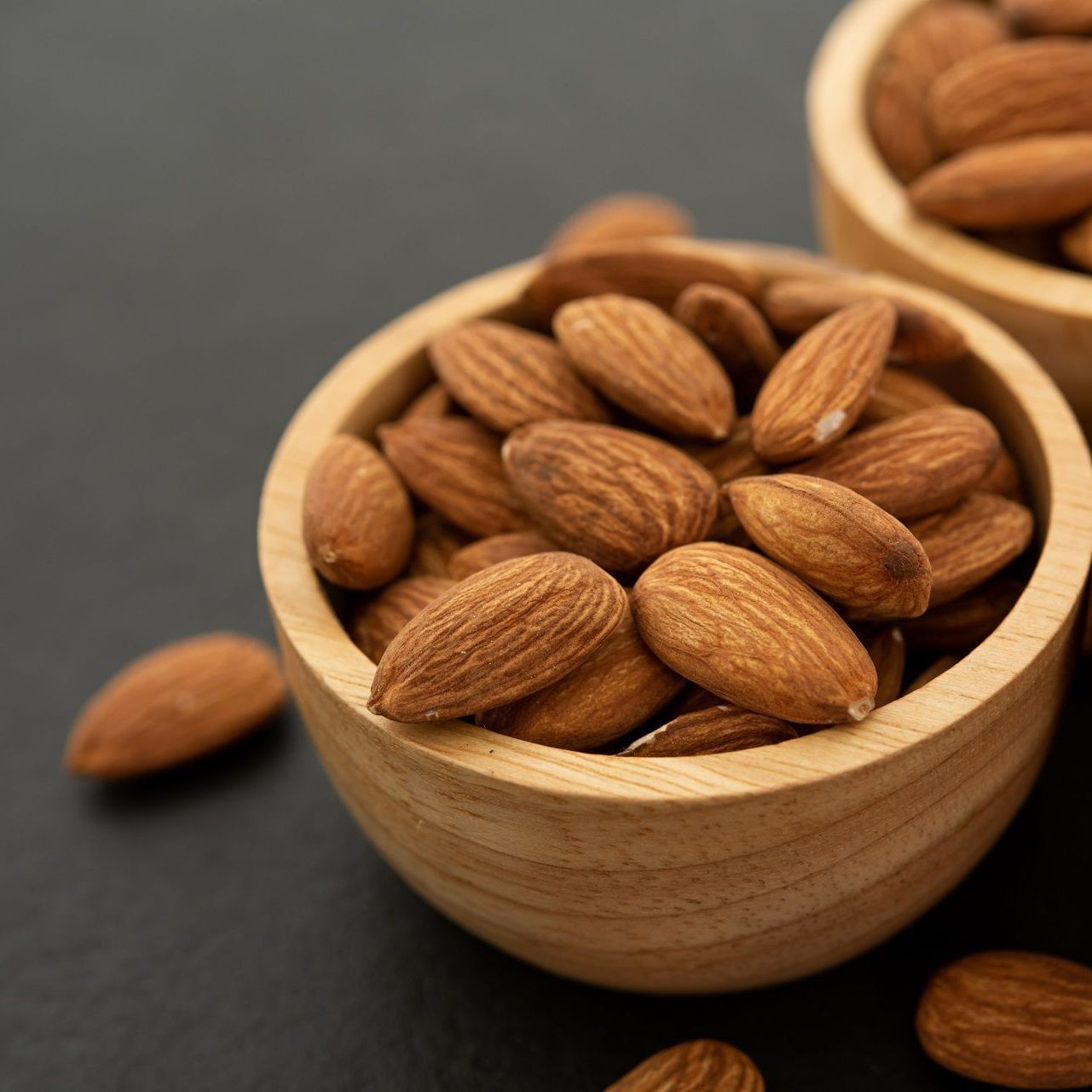 Two wooden bowls filled with almonds on a table