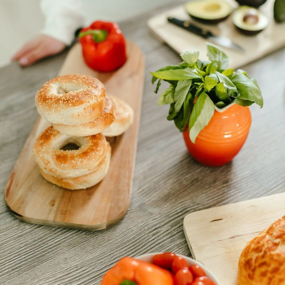 A wooden cutting board with bagels and peppers on it