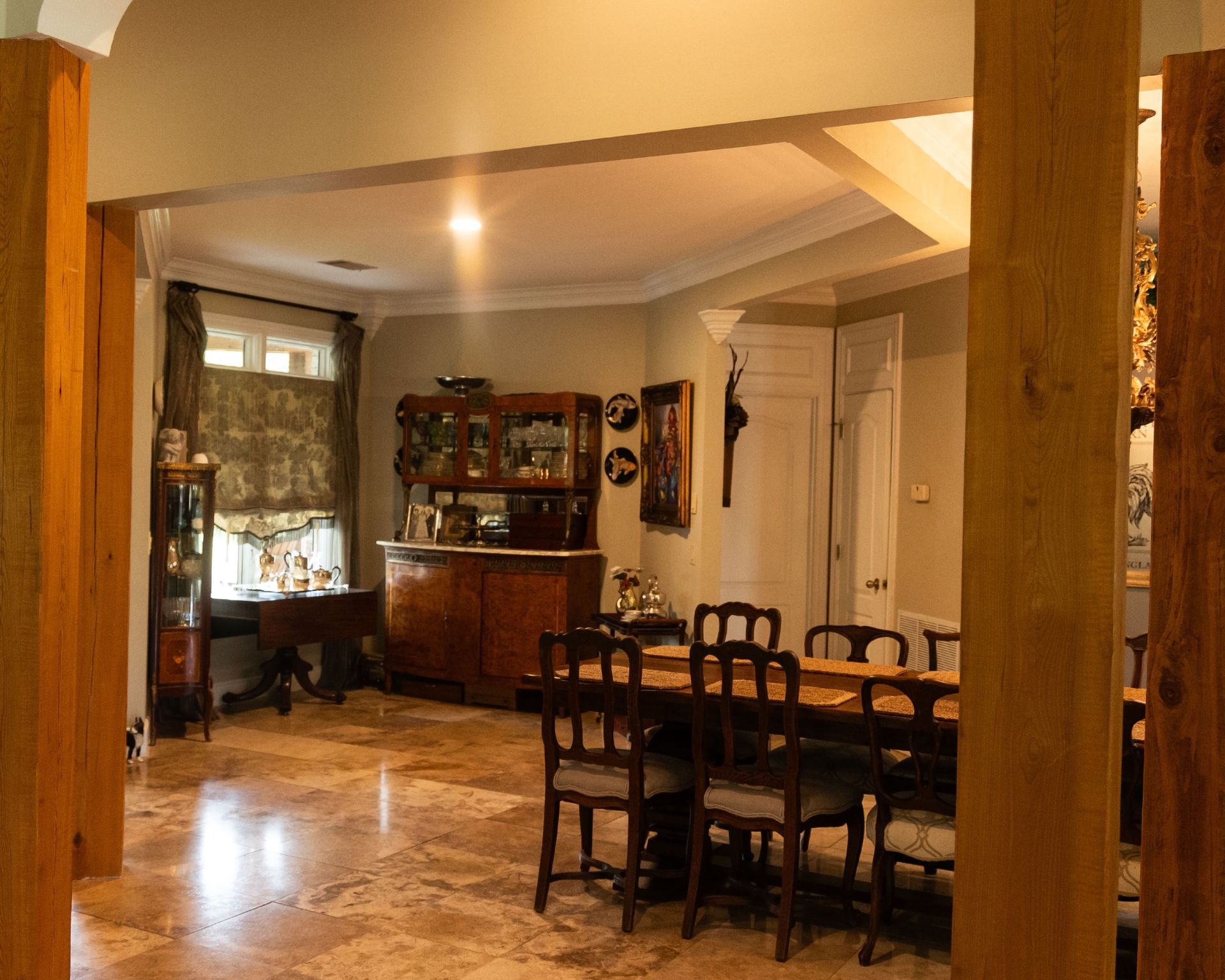 Warm dining room with wooden table, chairs, cabinet, and polished floor