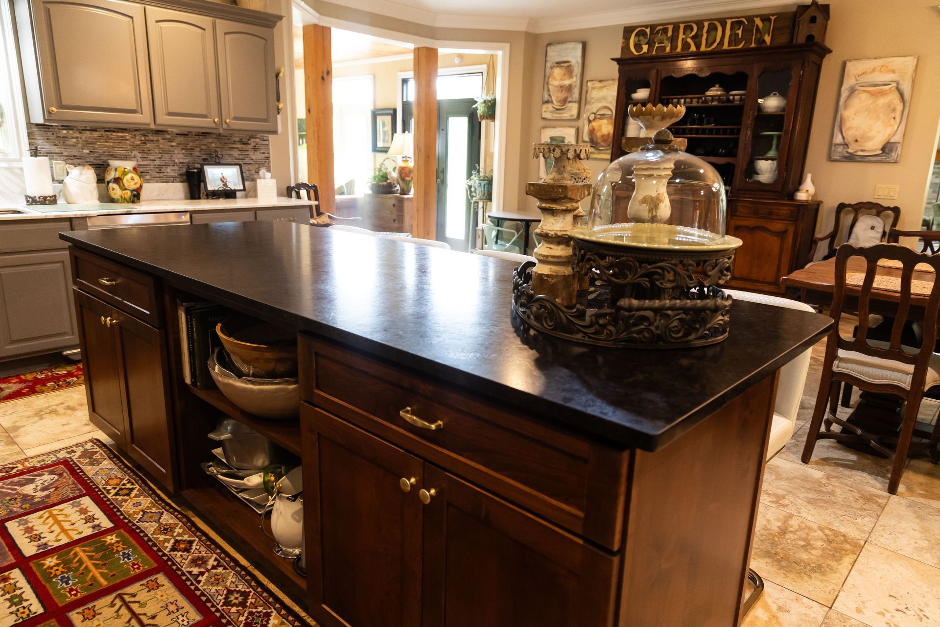 Spacious kitchen with a large black island, wood cabinets, and a dining area in the background