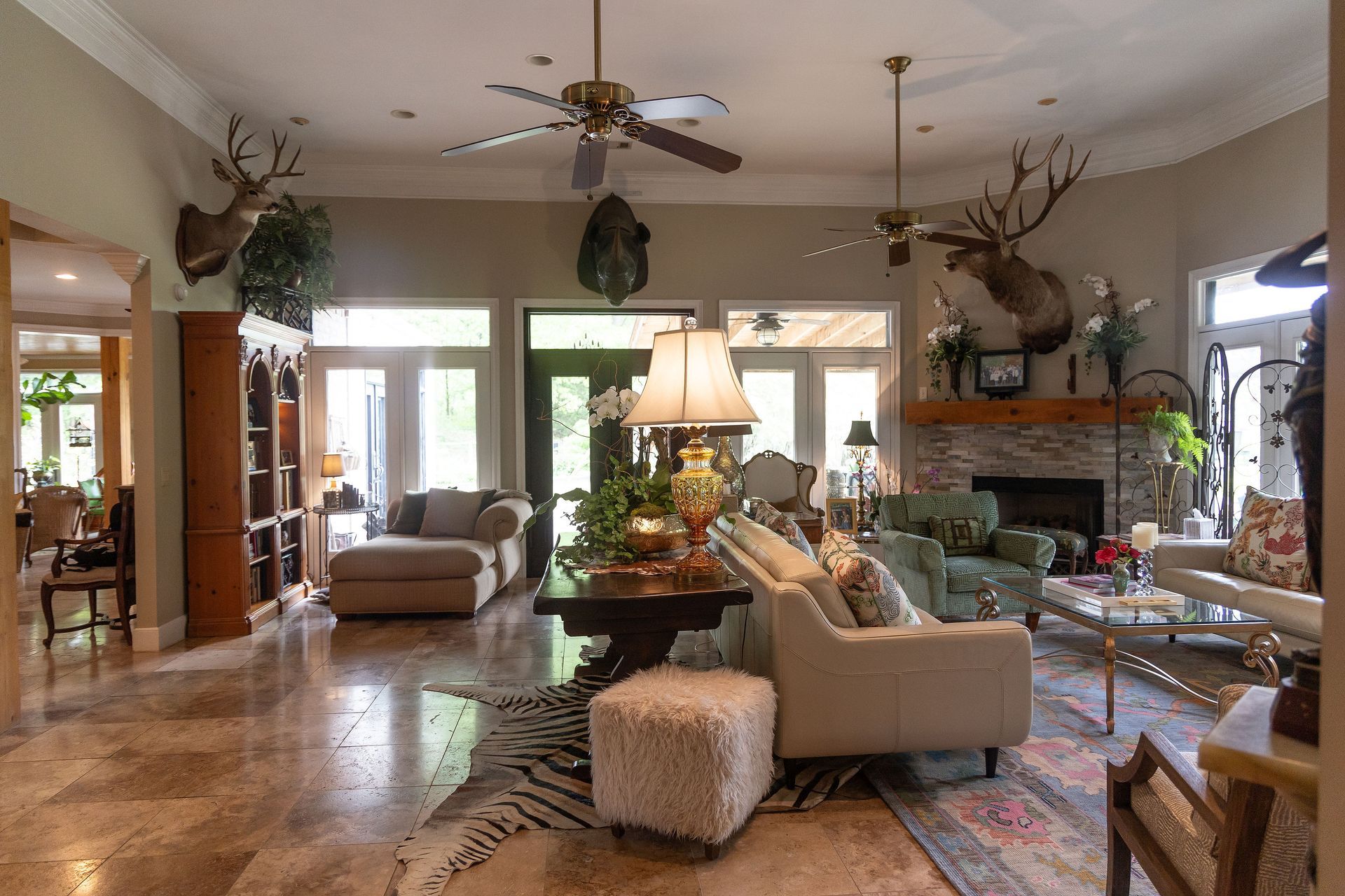 Spacious living room with beige seating, fireplace, large windows, and a central table with a lamp.