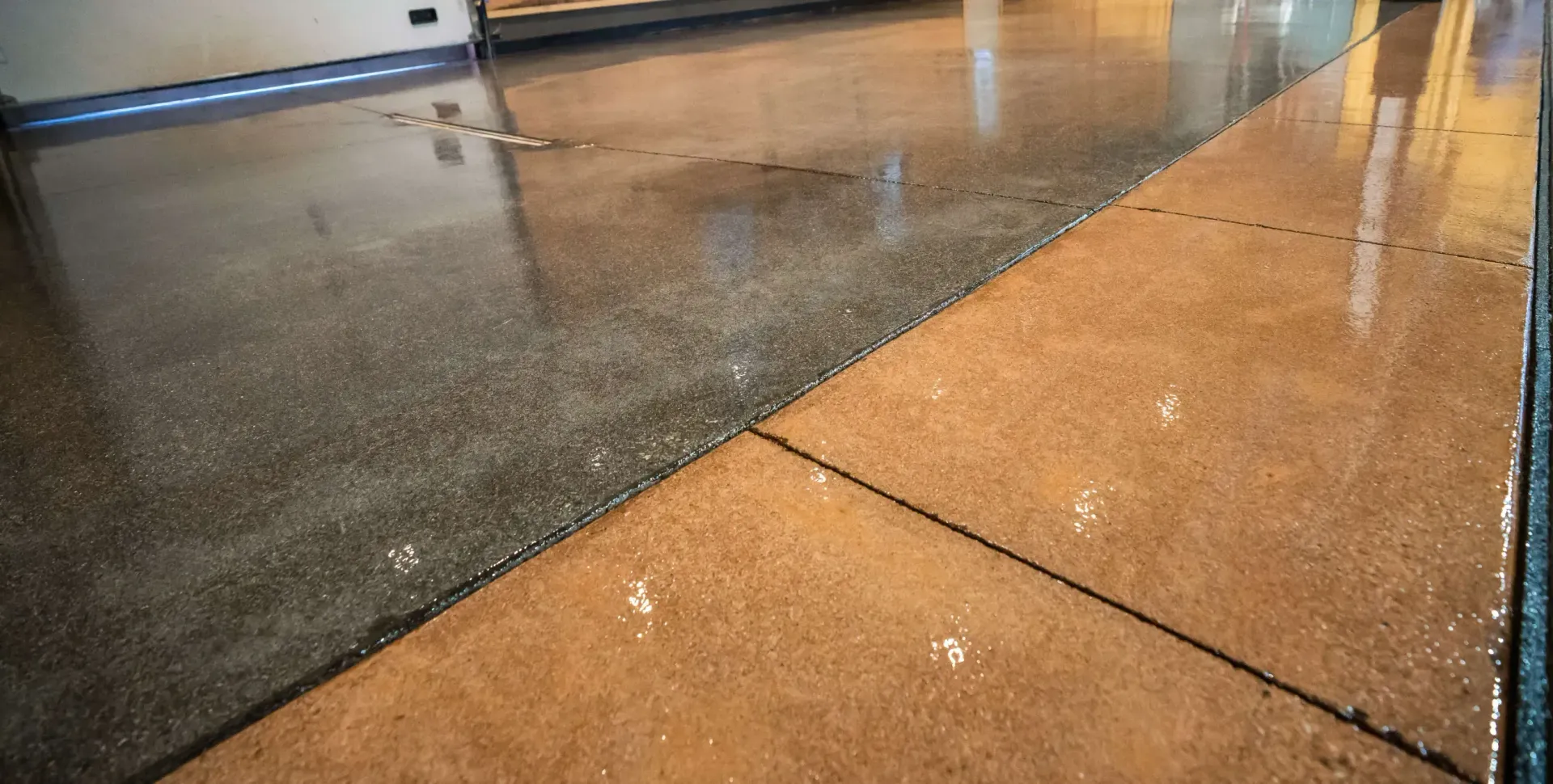 Wet indoor walkway with tan and dark-speckled flooring, reflecting overhead lights