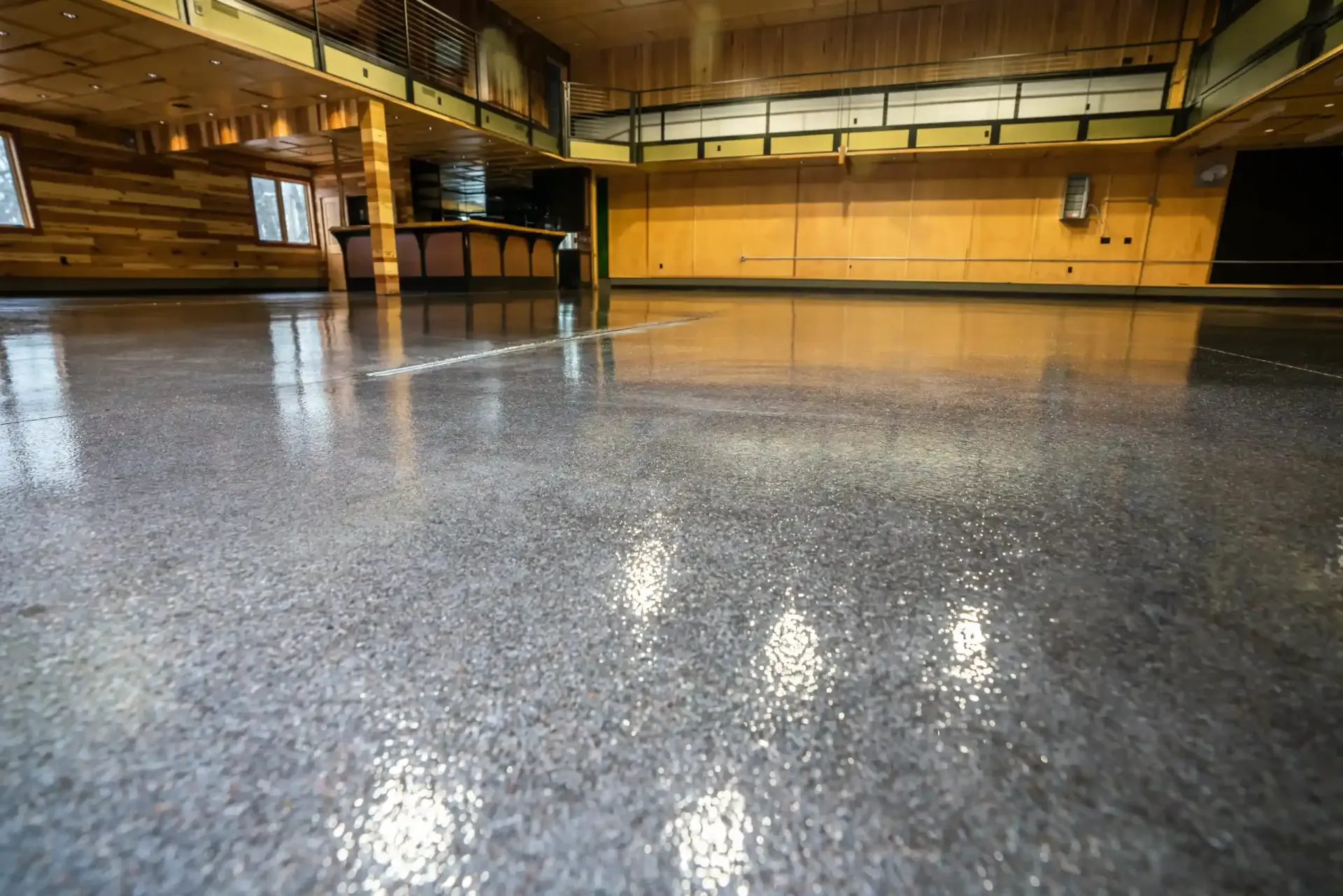 Empty indoor gymnasium with polished reflective floor and wooden walls