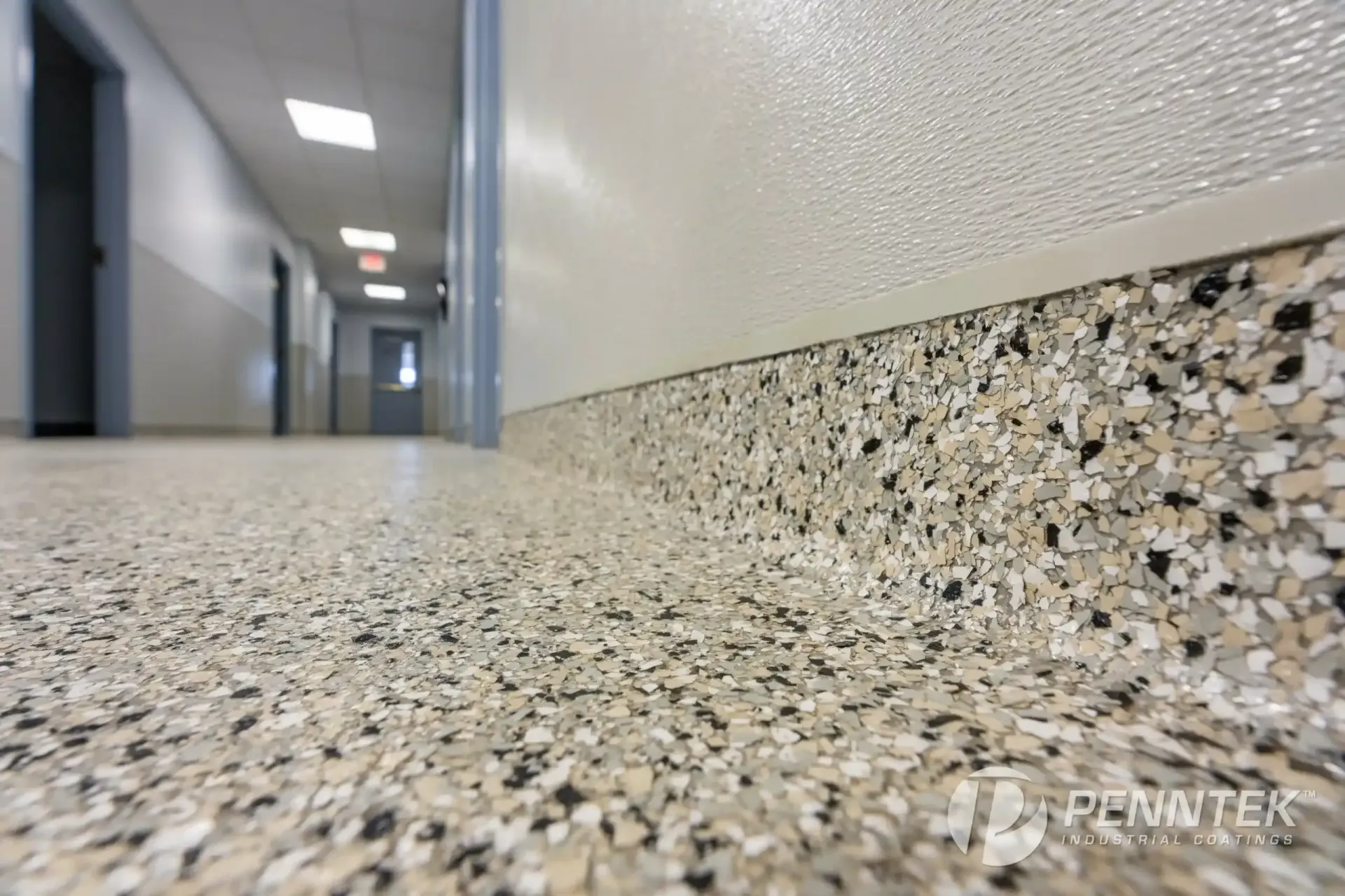 Low-angle view of a speckled hallway floor with white walls and doors in a building corridor