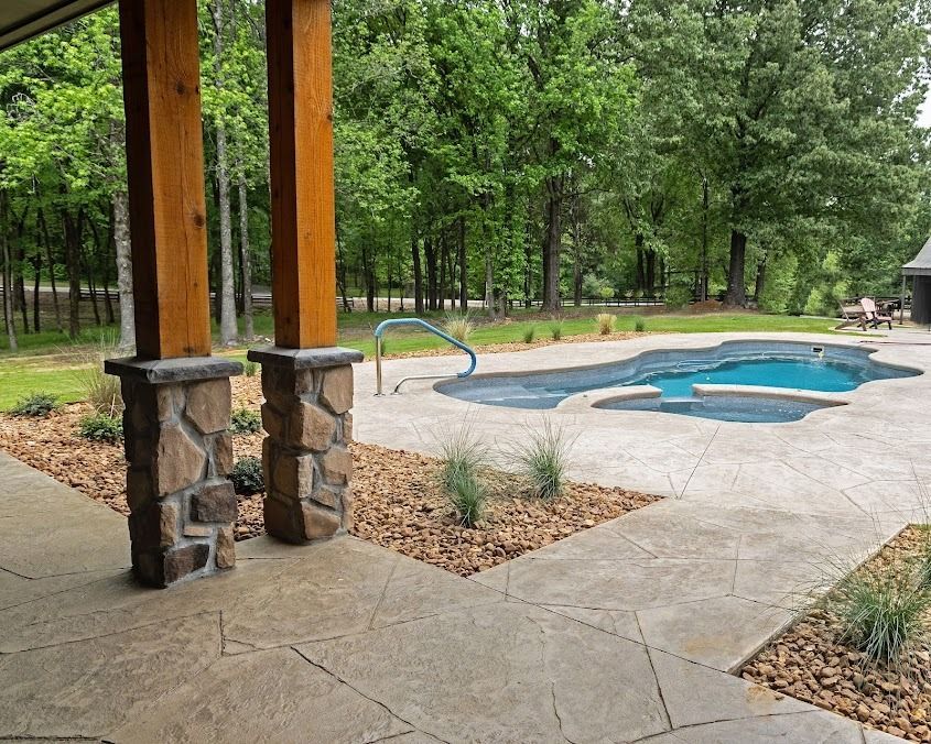 Covered patio overlooking a small backyard pool and hot tub surrounded by trees