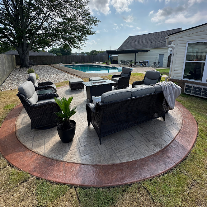 Backyard patio with wicker seating around a circular stone fire pit beside a swimming pool