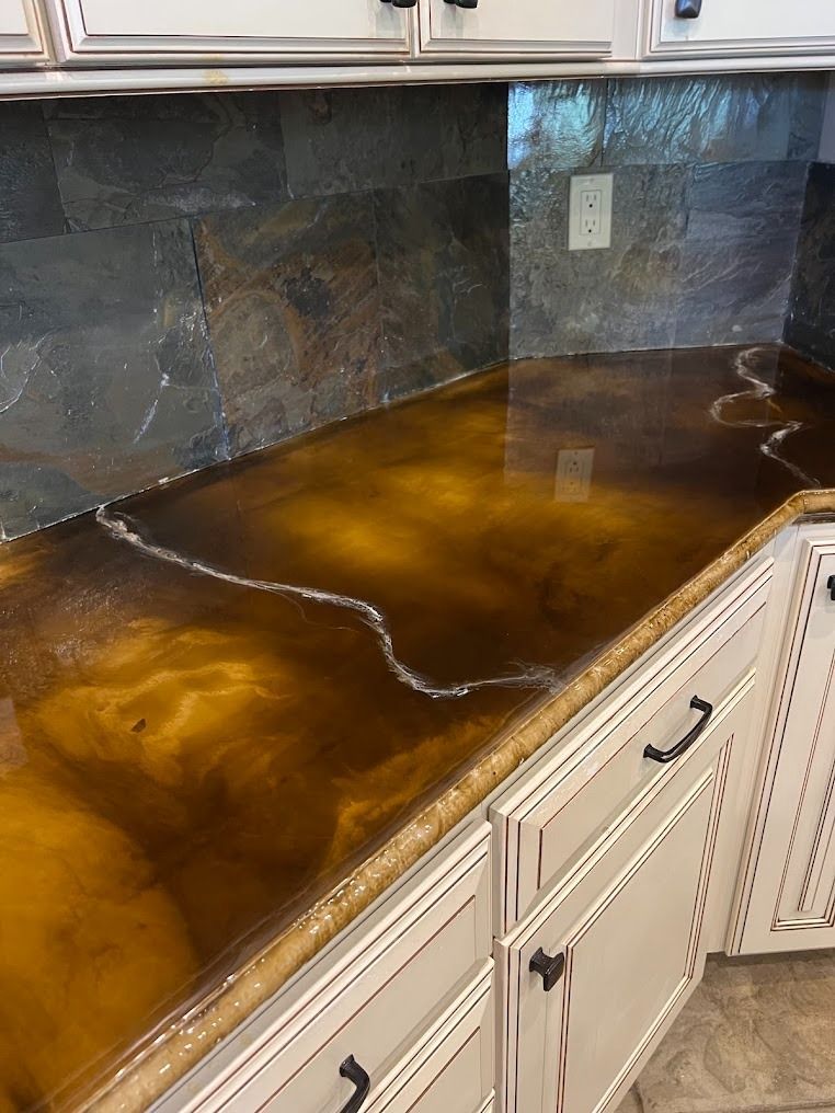 Amber resin kitchen countertop with a dark stone backsplash and cream cabinets